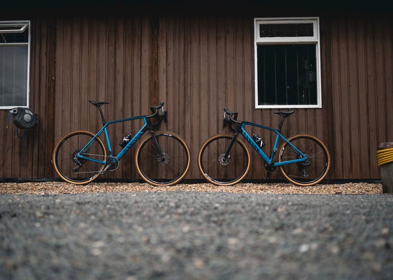 Two blue Canyon Grail CF gravel bikes leaning on a wooden building, like the loaners on offer for Grinduro Wales.