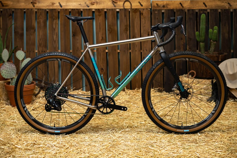 Prova Cycles Mostro titanium bike in teal and bronze paint with ENVE wheels, tan-wall tyres and two bottle cages.