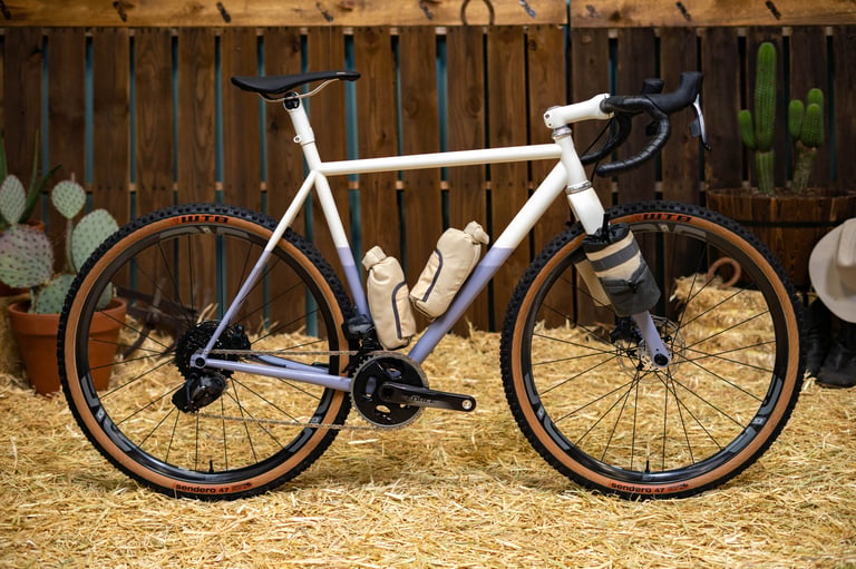 Speedvagen GTFO steel gravel bike in cream and lilac with tan cage bags and WTB Sendero tyres at the ENVE Builder Round-Up.
