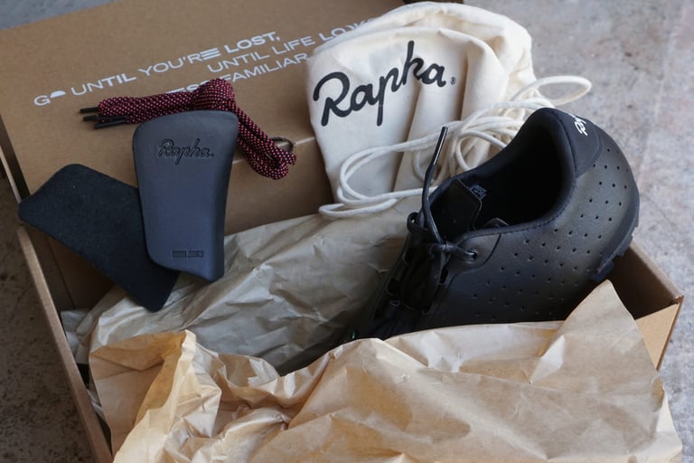 Rapha Explore Shoe in its box with the arch-support insoles, spare pink weave laces and a cotton shoe bag.