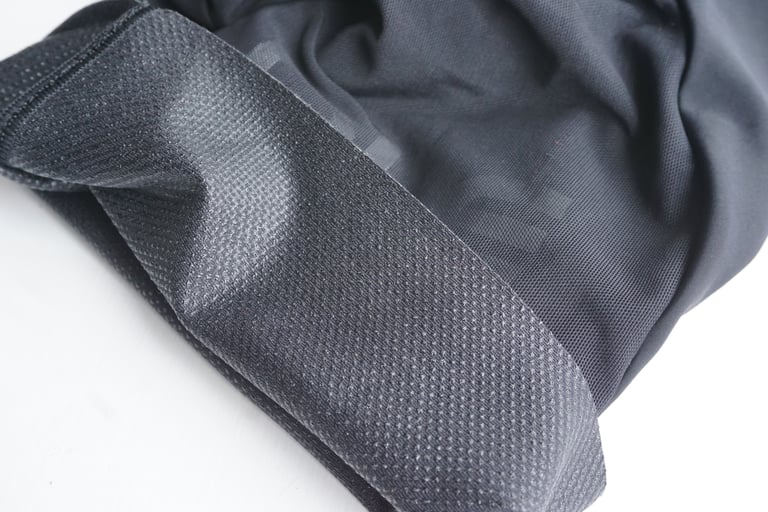 Inside of an Alé Stones bib short leg hem showing the wide silicone-dot leg gripper on black fabric.