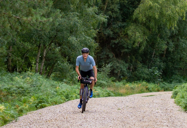 Rider on the Salsa Warbird heads towards the camera along a wide gravel fire road through Thetford Forest.