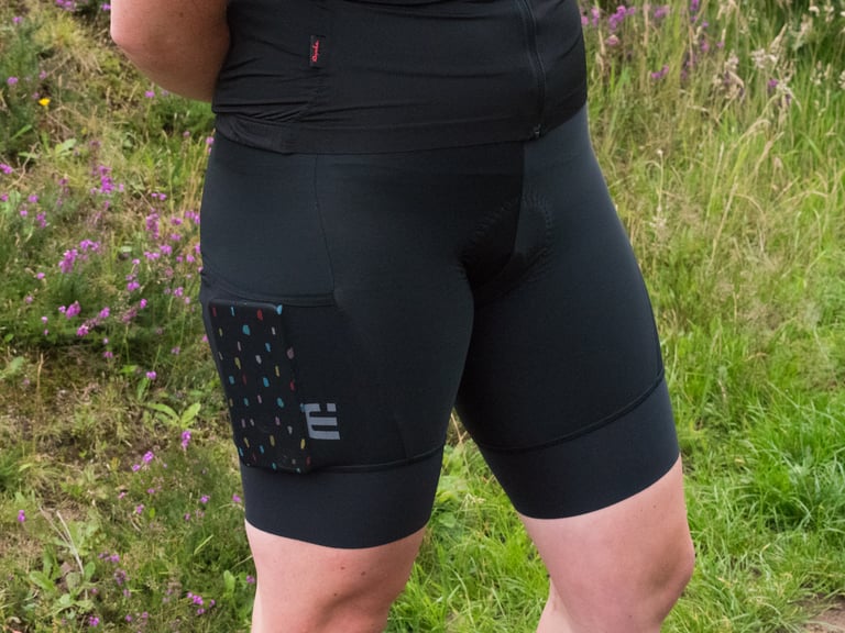 Alé Stones cargo bib shorts worn on a trail with a phone held in the mesh thigh pocket.