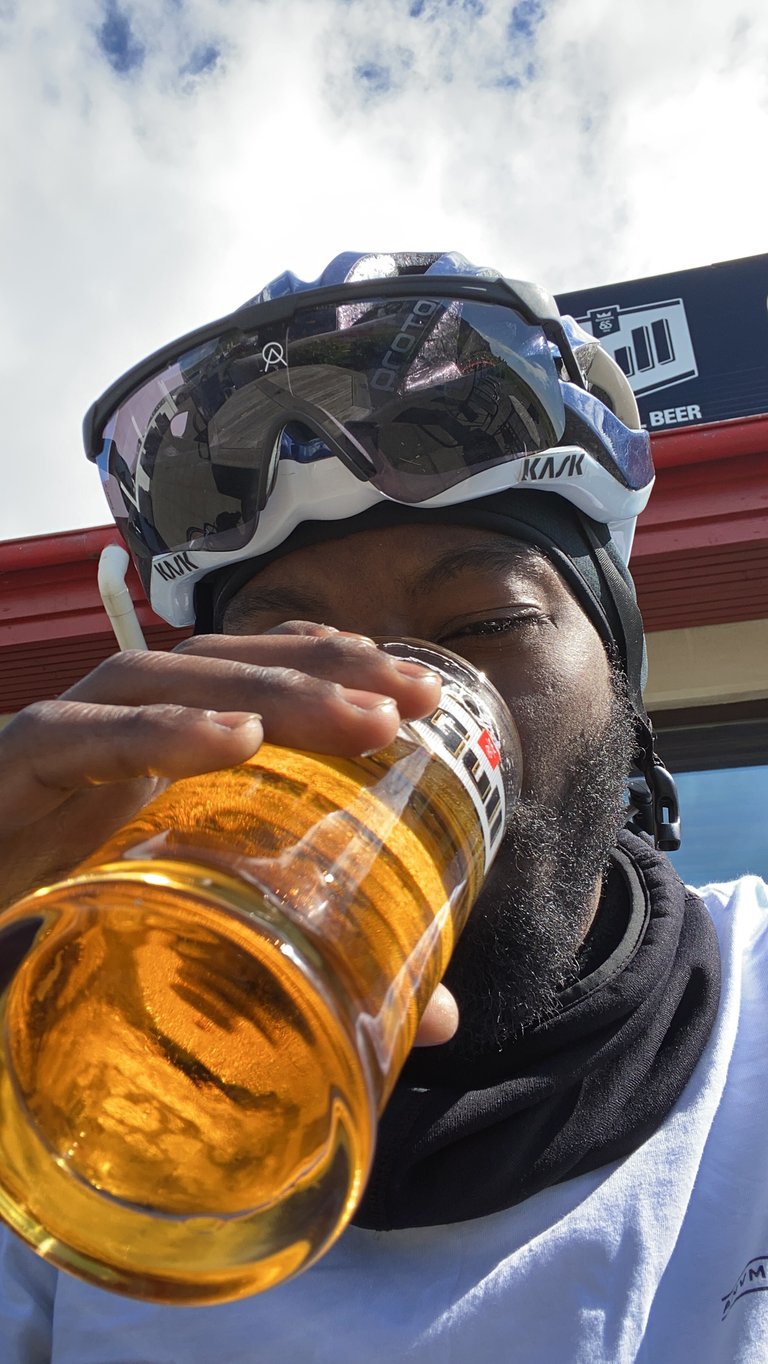Natt Williams, still in Kask helmet and sunglasses, drinks a victory pint in Vik after finishing the Iceland Divide.