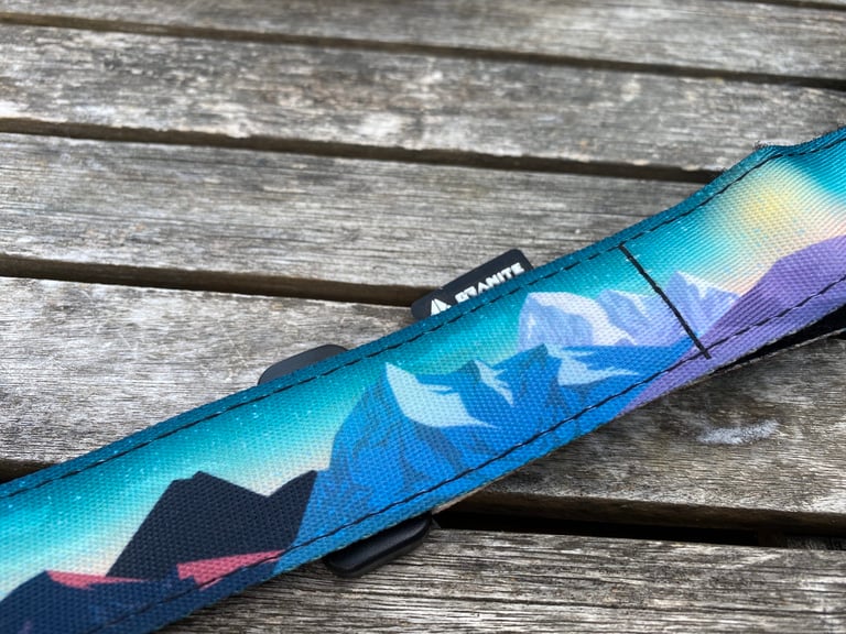 Granite ROCKBAND+ strap with a blue and purple mountain print lying on a weathered wooden table.
