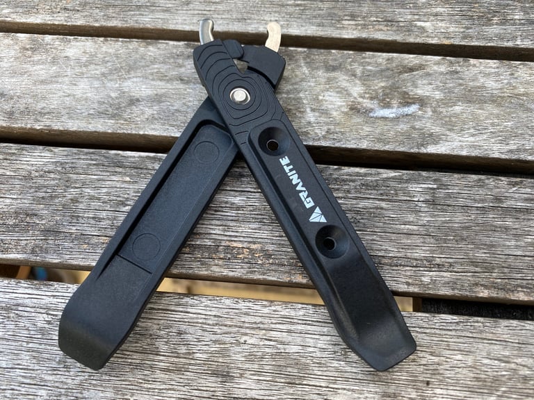 Granite TALON tyre levers clicked together to form the quick-link pliers, on a wooden table.