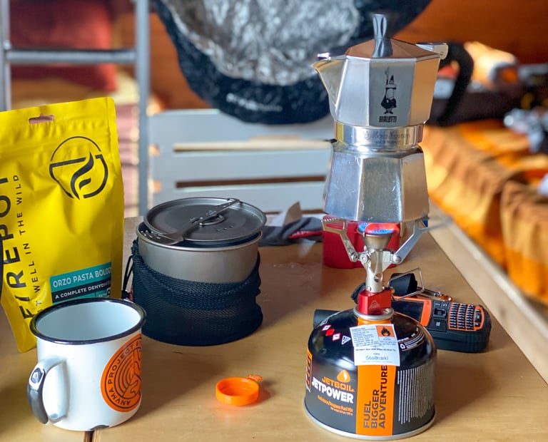 Bialetti Moka pot on a gas stove beside a Firepot meal pouch and Jetboil canister, Natt's Iceland Divide cooking kit.