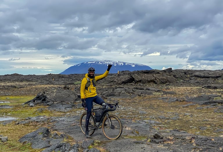 Natt Williams raises a fist astride his loaded bike on black lava fields at the start of the Iceland Divide.