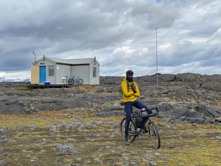 Natt Williams sits on his loaded bike outside Botni Mountain Hut, a small corrugated hut on lava fields in Iceland.