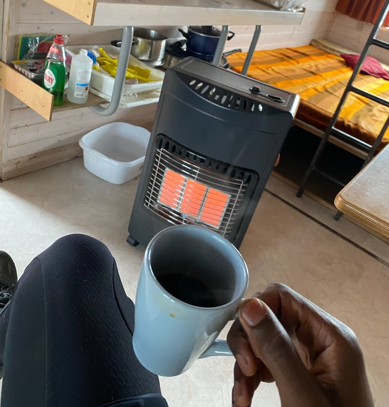 Mug of coffee held in front of a gas heater inside Dyngjufell mountain hut on the Iceland Divide.