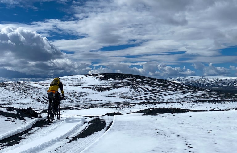 Natt Williams rides his loaded gravel bike along tyre tracks in snow on day three of the Iceland Divide.