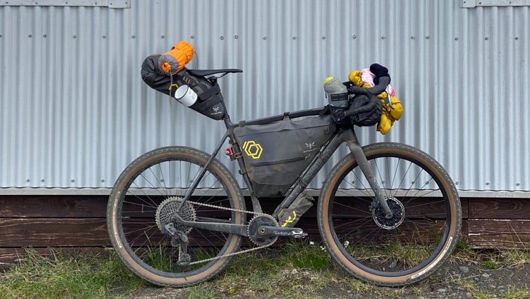 Natt Williams's Bombtrack Hook EXT-C set up for the Iceland Divide with Apidura bags, against a corrugated wall.