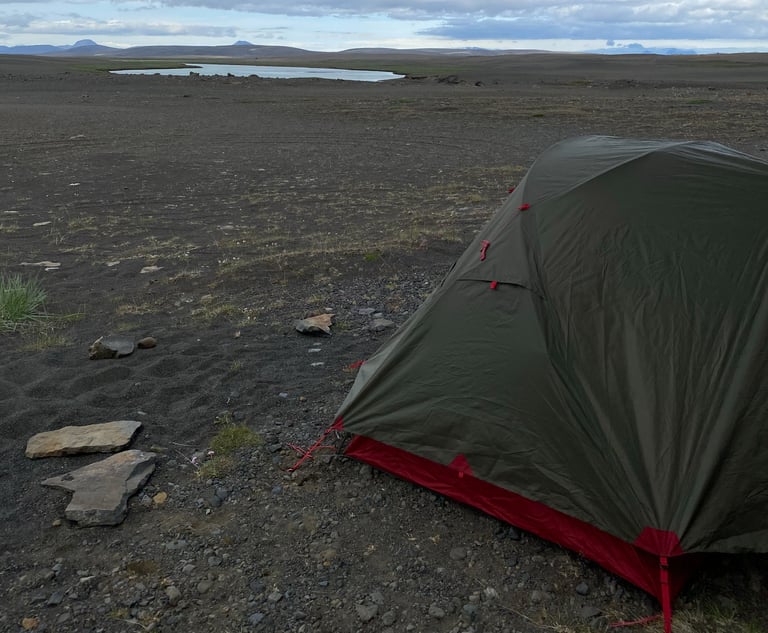 MSR Elixir 3 tent pitched on black volcanic grit, a lake and bare hills behind, in the Icelandic highlands.