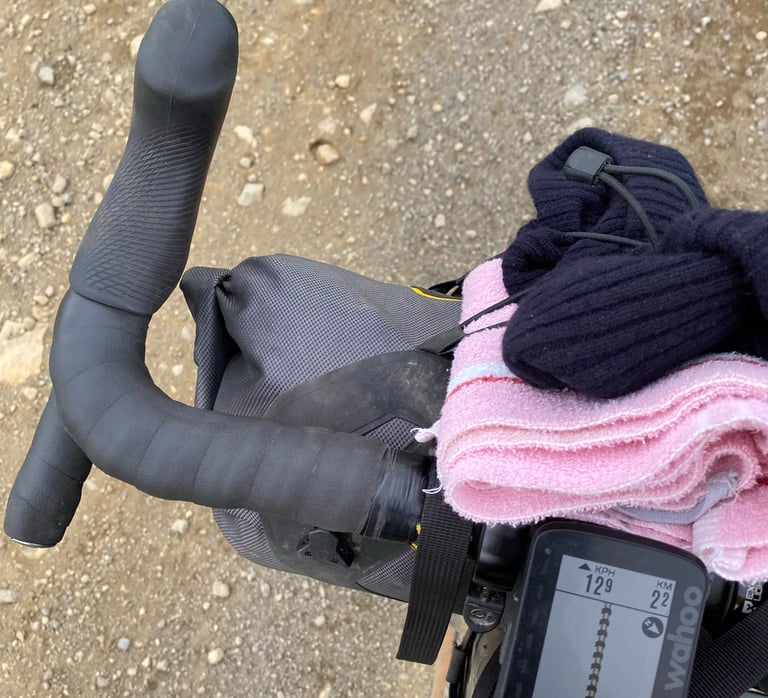Pink towel strapped to the Apidura handlebar pack beside a Wahoo ELEMNT ROAM, ready for Iceland Divide river crossings.