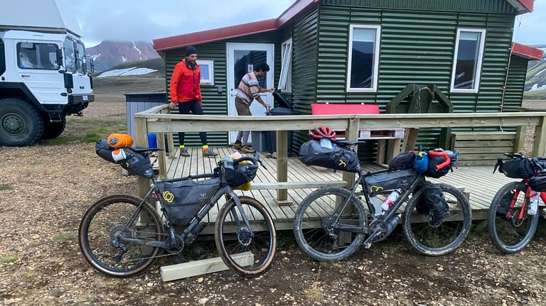 Three loaded bikepacking bikes lean against the deck of the green Alftavant mountain hut in the Icelandic highlands.