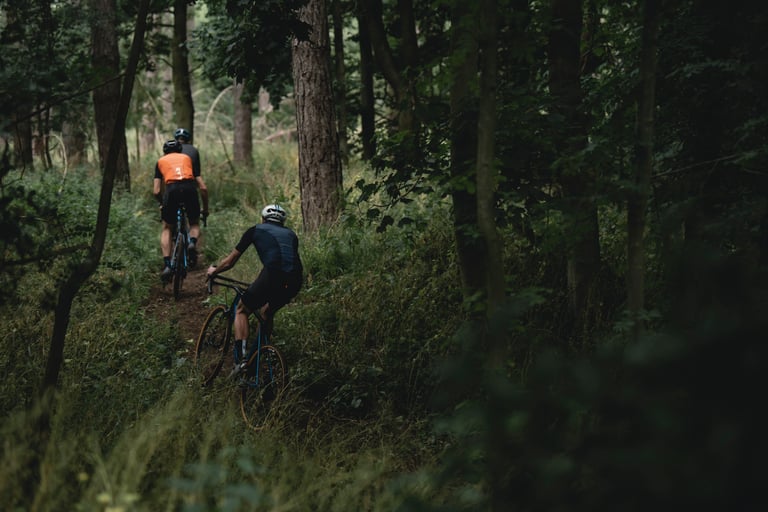 Two riders thread singletrack through dense woodland, a taste of the twisting trails in the King's Cup forest.