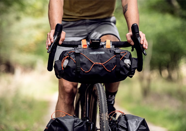 Updated Ortlieb handlebar pack with non-slip buckles and orange bungee cord, fitted to a drop-bar gravel bike.