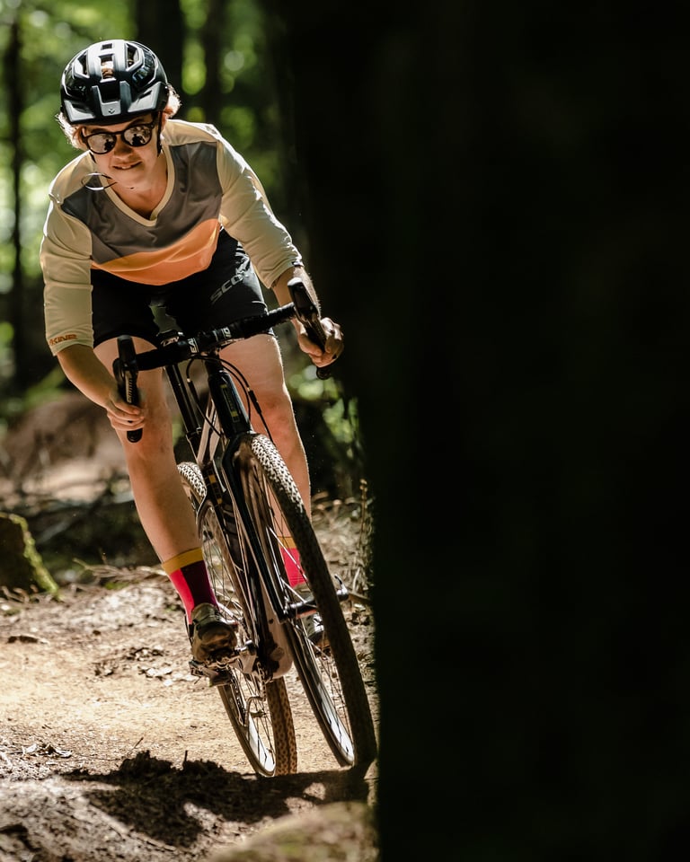 Monet Adams leans into a turn on a gravel bike through shaded woodland on WTB Resolute SG2 tyres.