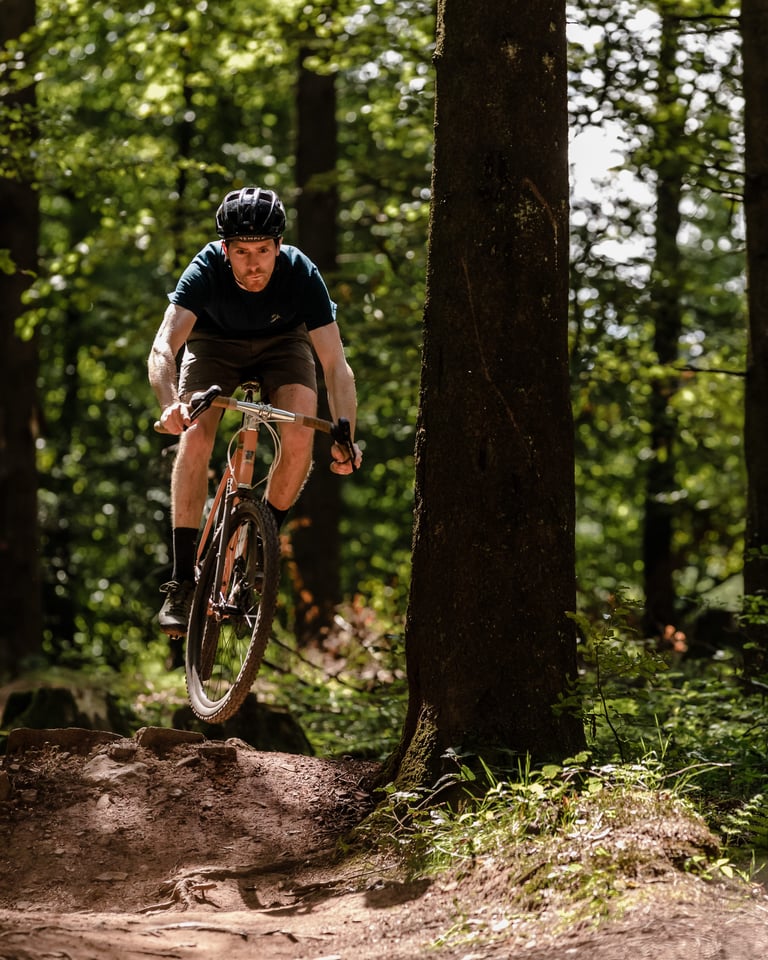 James Stockhausen airborne on a gravel bike over a woodland jump, riding WTB Sendero SG2 tyres in the Mendips.