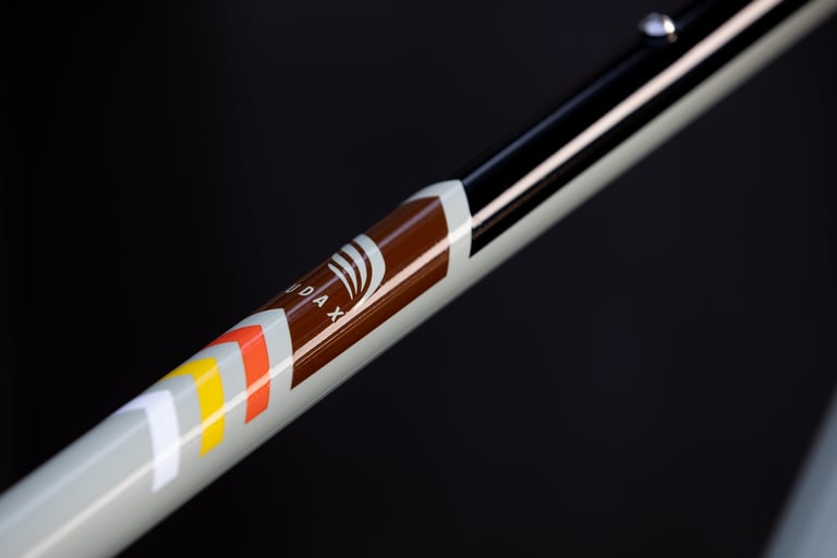 Close-up of the Audax decal and brown, orange and yellow chevrons on a sage green tube of the 2021 Bombtrack Audax.