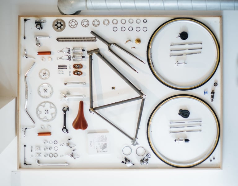 Exploded flat-lay of a Temple Classic bike before paint, with frame, wheels and components laid out on white.