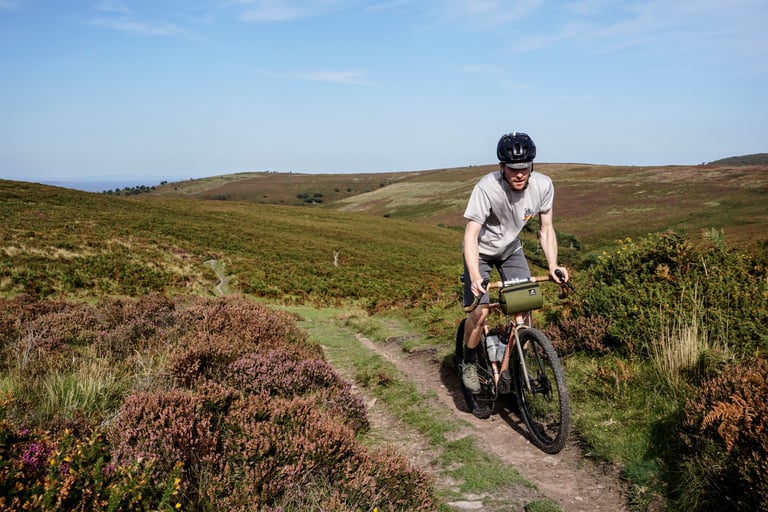 James from Temple Cycles rides his Adventure Disc with flared Salsa Cowchipper bars up a heathery Quantock Hills track.