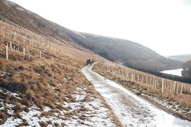 Winter riders on a snowy track above a reservoir in the Peak District on a chilly February morning.