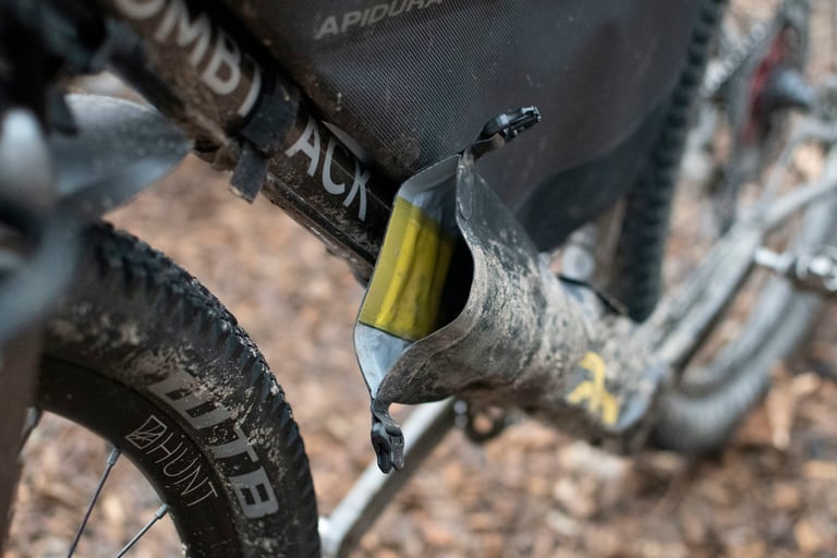 Roll-top opening of an Apidura Expedition Downtube Pack mounted under the down tube of a Bombtrack bike.