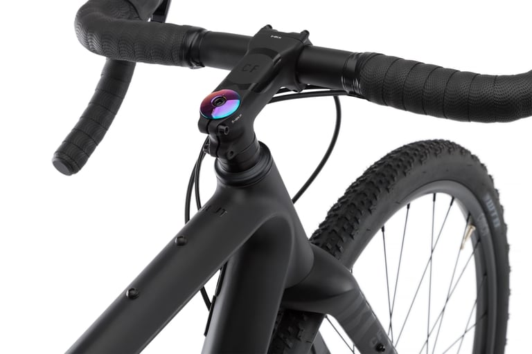 Close-up of the black Rondo Ruut CF2 stem, Spank Wing Vibrocore handlebar and head tube with an oil-slick top cap.