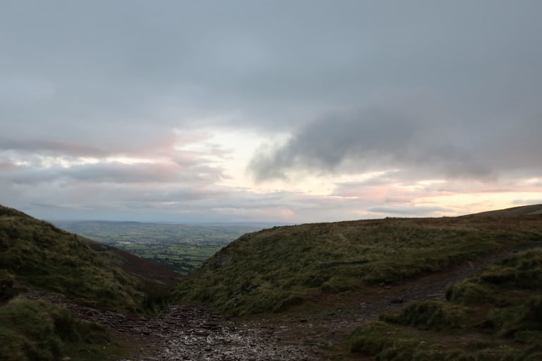 Early morning light over a rocky, wet track at The Gap, with the valley opening out below, in the Brecon Beacons.