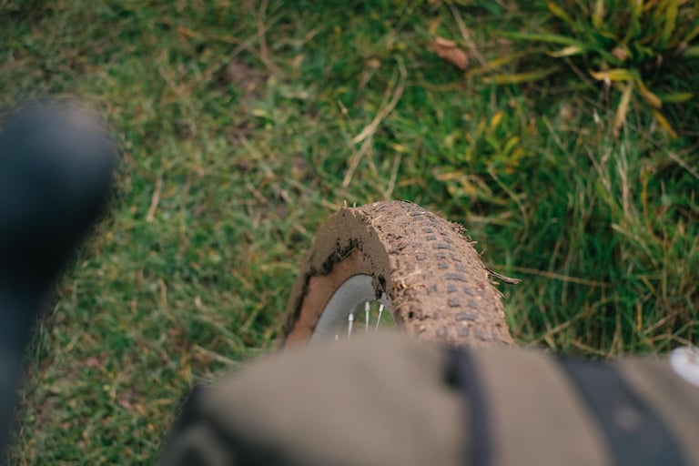Front tyre caked in clay, seen from the saddle, on the claggy stubble-field crossings of the Kent ride.