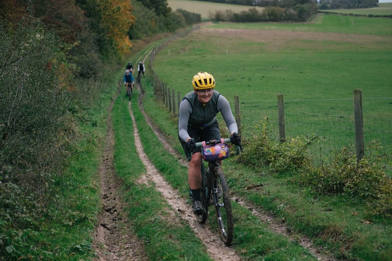 Rider in the Velocio Micromodal long sleeve jersey climbs a grassy track on a Kent gravel ride, others following.