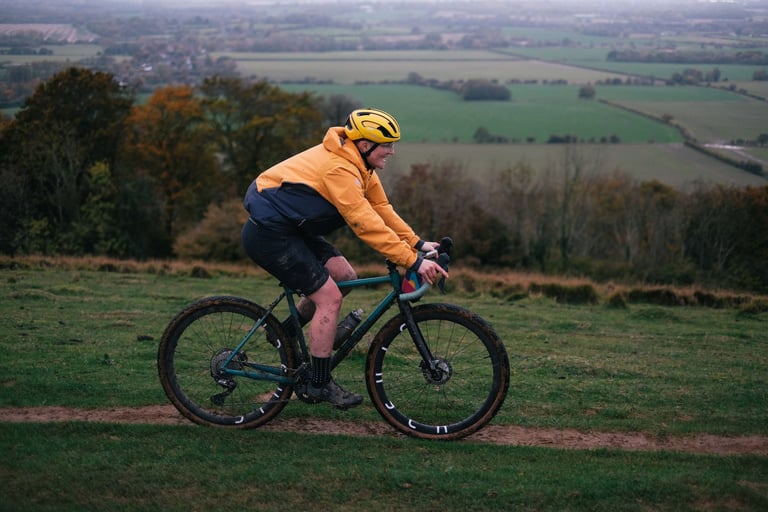 Rider in a yellow helmet on a Stayer Groadinger UG rides a hilltop track above patchwork fields on the Wye Downs, Kent.