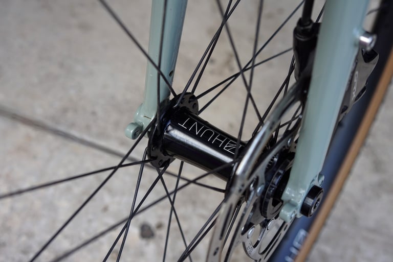 Black Hunt hub and disc rotor on the front wheel of the Temple Adventure Disc 1, between pale green fork legs.