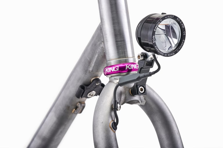 SON Edelux II dynamo light on the fork crown of the raw steel Fairlight Faran 2, with the cable routed into the fork.