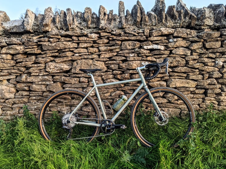 Temple Adventure Disc 1 in Lichen Green leaning against a Cotswold dry-stone wall.