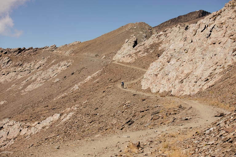 Badlands rider pushes a bike up the rocky track towards Pico del Veleta in the Sierra Nevada.