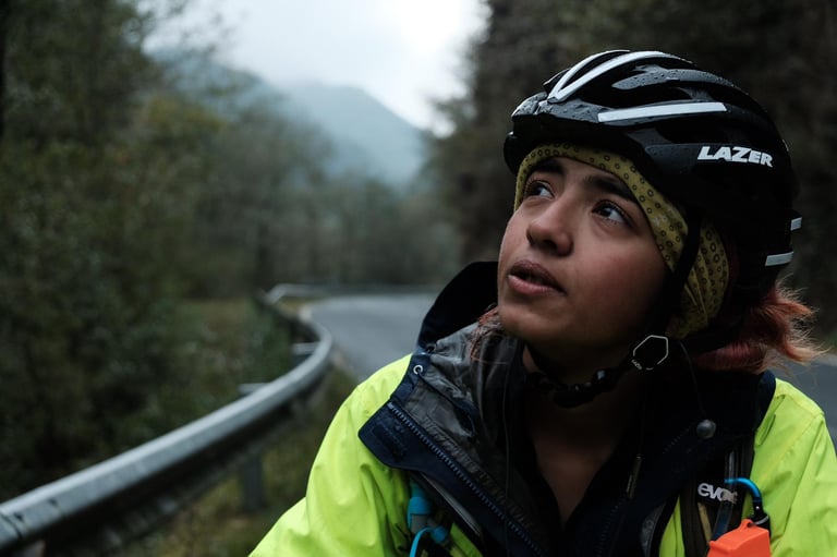 Vedangi Kulkarni in a Lazer helmet and hi-vis jacket looks up at the sky on a damp, misty road.