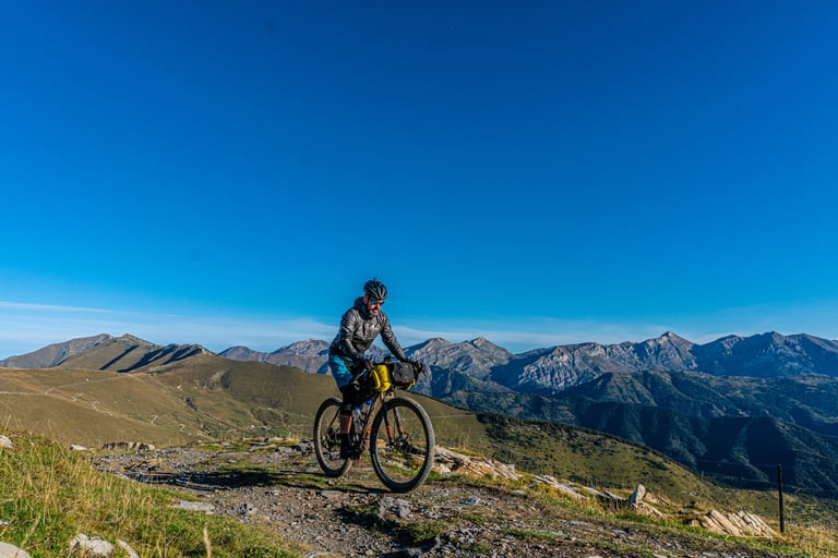 Rider on a Shand Bahookie fitted with Curve Walmer bars rides a high ridgeline trail with mountain peaks behind.