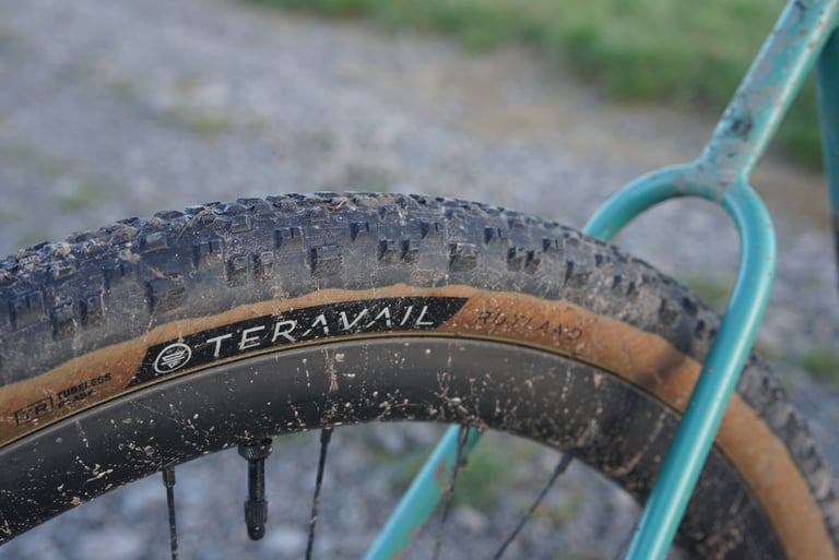 Teravail Rutland 650b x 47 mm tyre with tan sidewall, spattered with mud, on a teal Stayer Groadinger UG.