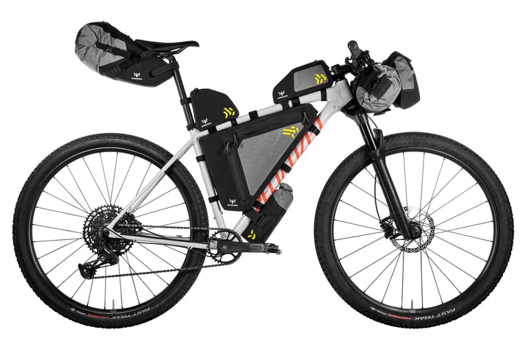 Specialized hardtail with the full Apidura Backcountry bag set, saddle pack to handlebar pack, on white.