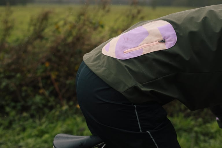 Lilac and cream rear pocket patch with a pink zip on the back of the IRIS Escape Jacket, seen from the side.