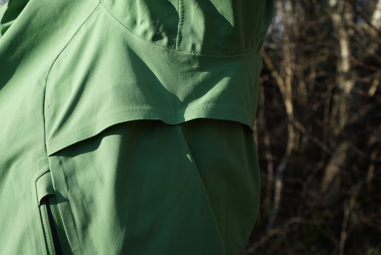 Close-up of the Alpkit Balance underarm vent, a fixed, permanently open flap in green fabric above a pocket zip.