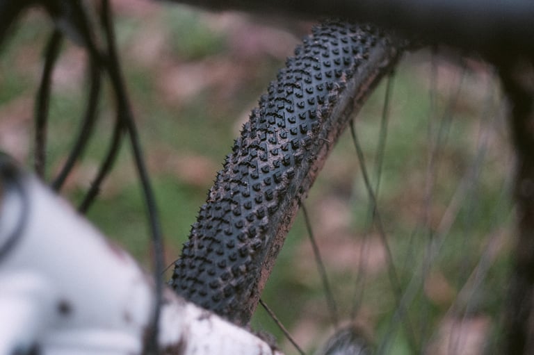 Mud-caked Halo GXC gravel tyre on test, seen from the front of a bike on a grassy trail.
