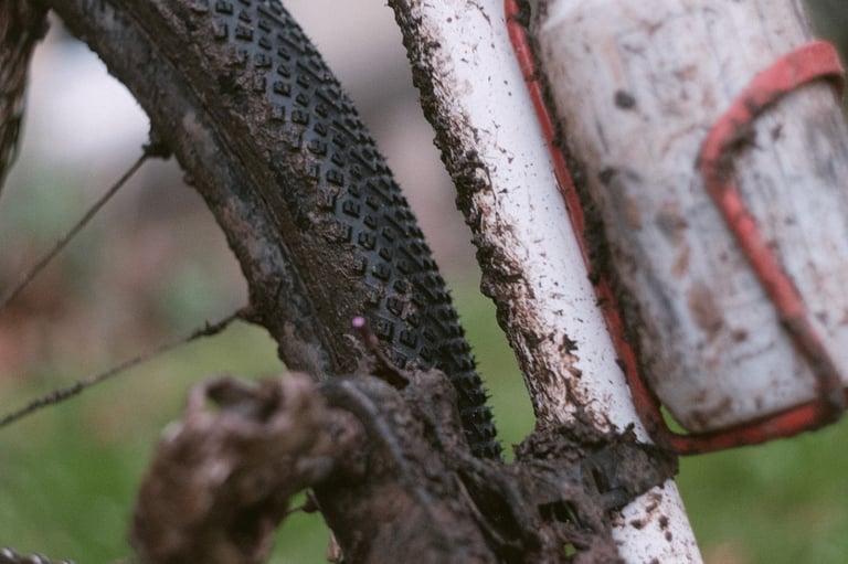 Halo GXC tyre tread clogged with mud beside a mud-splashed frame and red bottle cage.