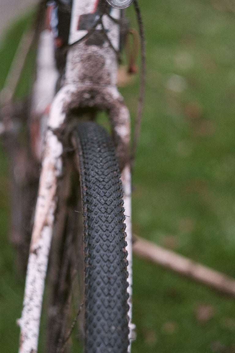 Front Halo GXC tyre seen head-on, held in a muddy white fork on a grass verge.
