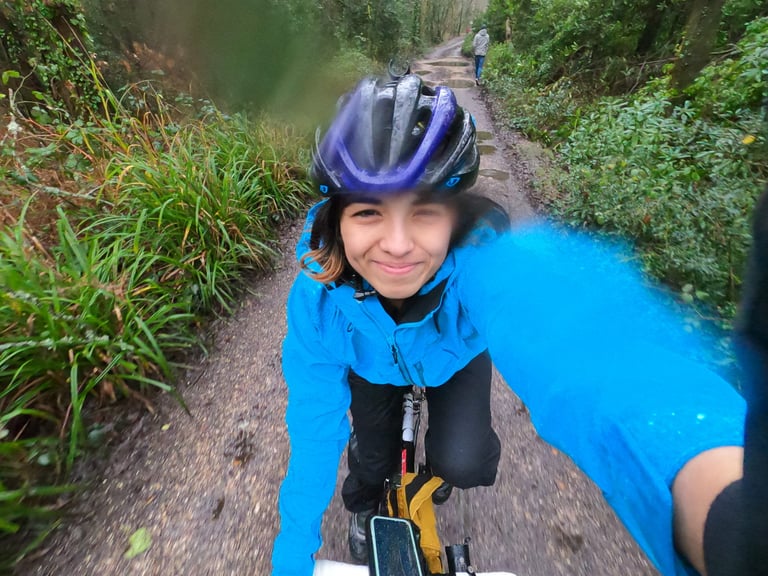 Smiling rider in a wet Madison DTE jacket takes a selfie while riding a muddy track in the rain.