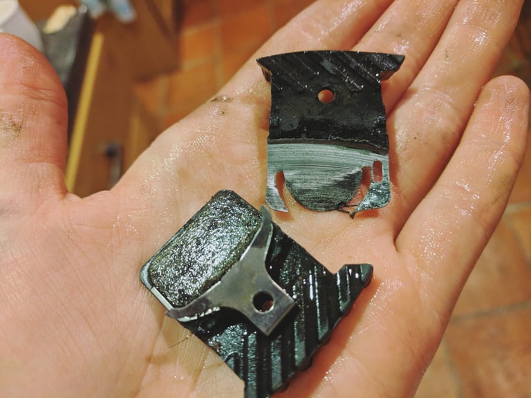 Worn-out disc brake pads held in a palm after a muddy Festive 500 off-road attempt.