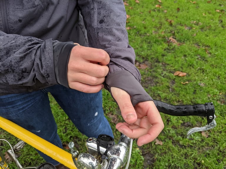 Findra Stroma jacket cuff with a thumb hole, the wearer pulling the stretchy sleeve over the back of the hand.