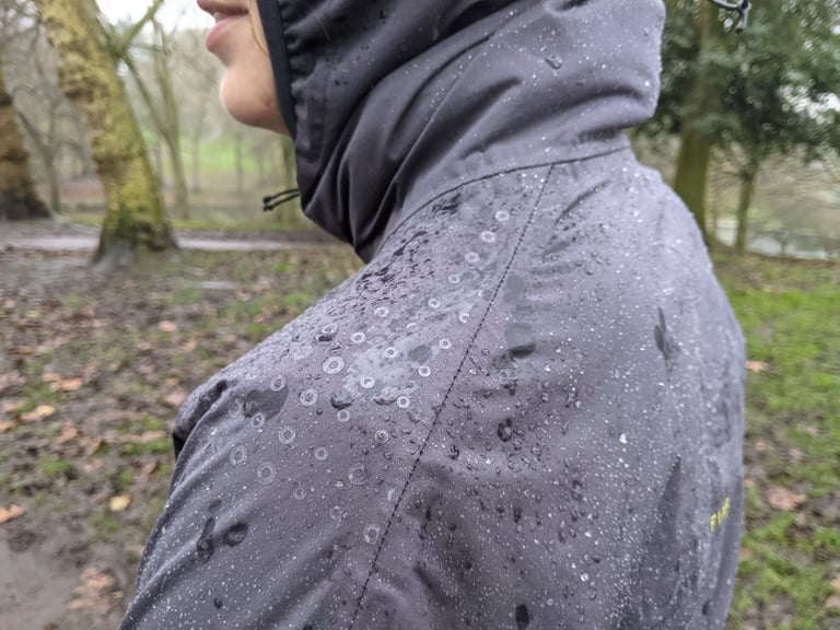 Close-up of rain beading on the shoulder and hood of the Findra Stroma jacket after repeated washes.